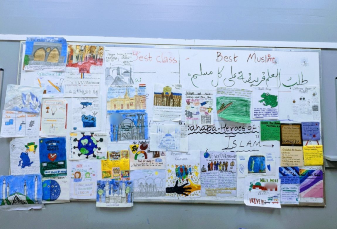 A classroom display wall covered in children's project work: mosques of Cordoba and Istanbul, Islamic universities, science posters and profiles of the Sahaba